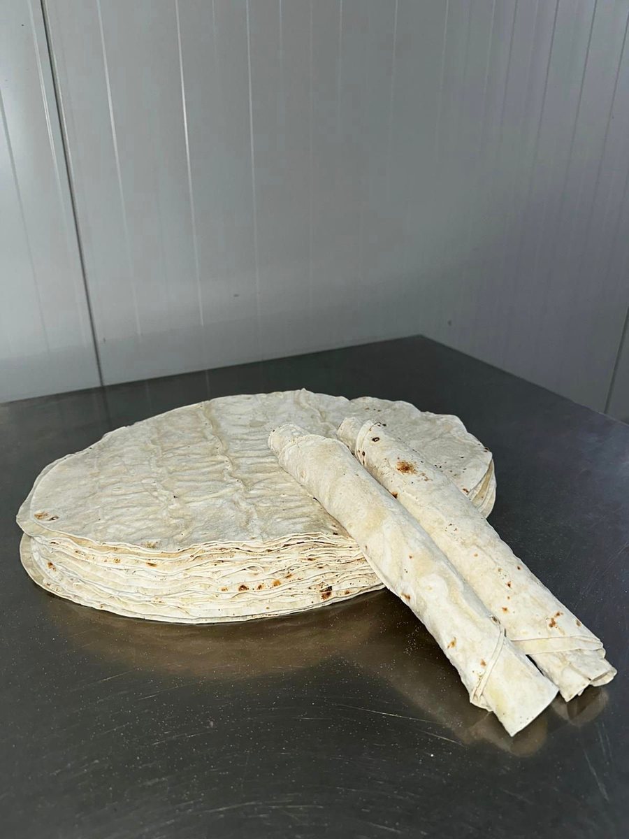 A round stack of dürüm lavaş on a stainless steel work table in the bakery