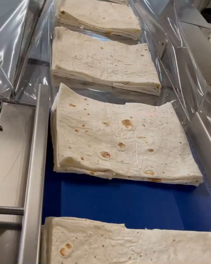 Folded packs of yufka on the blue conveyor, heading under the film